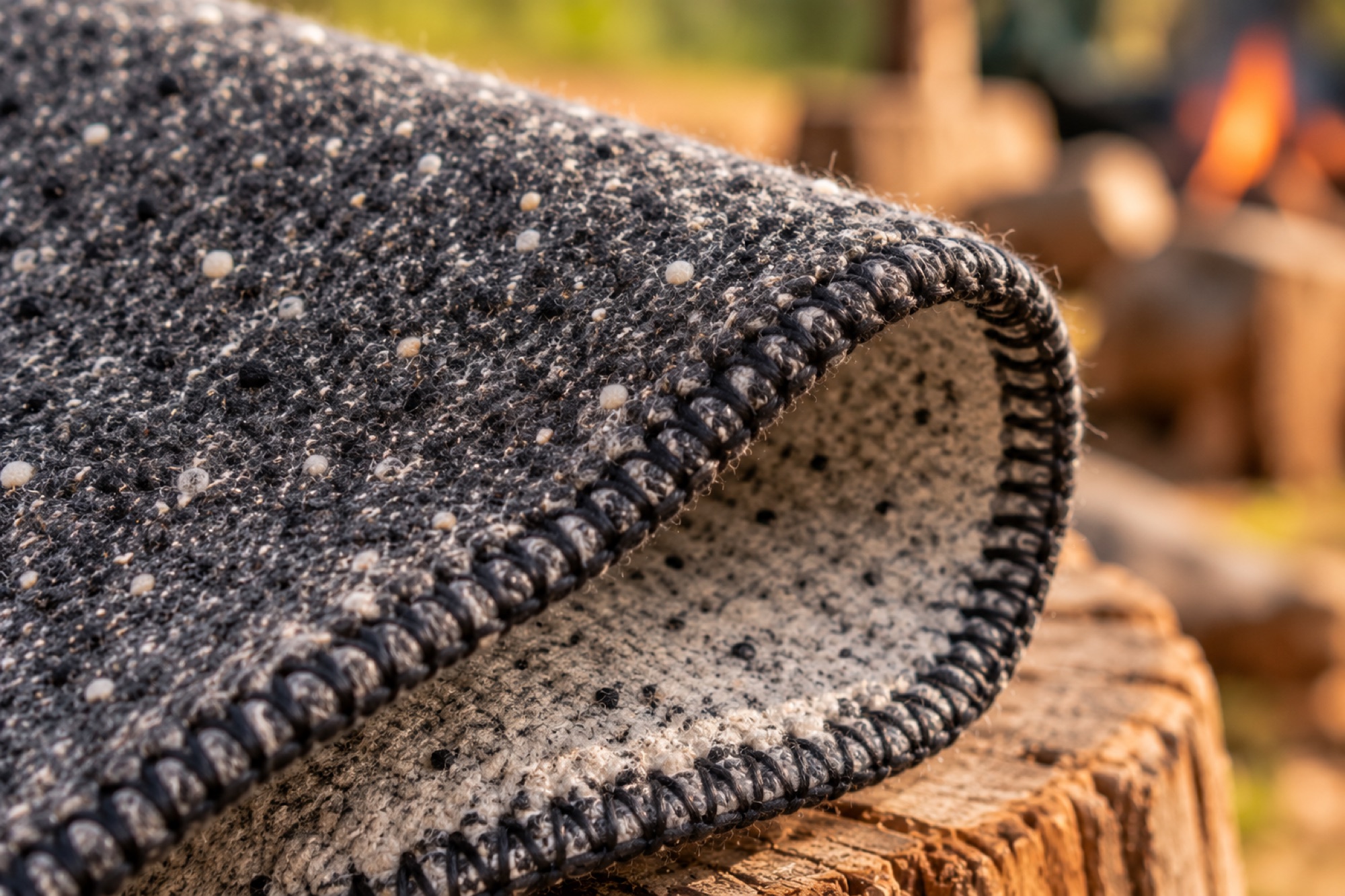 Close-up of the black blanket-stitch edge where the blanket rolls over from charcoal to cream