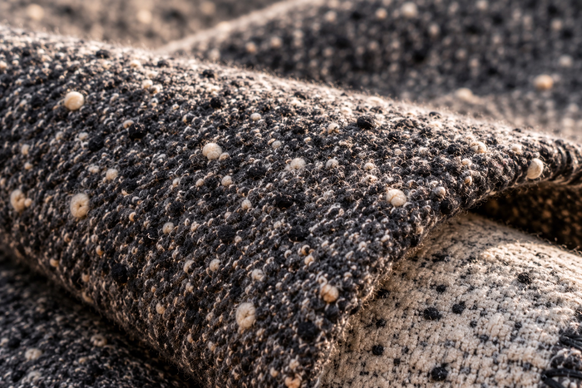 Close-up of the charcoal weave, flecked with cream, folded over the lighter reverse